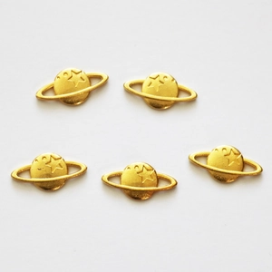 Detailed view of five golden planet charms for DIY jewelry making on white background