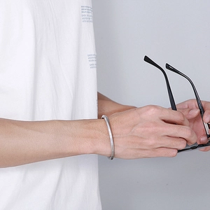 Gros plan d'un bracelet jonc torsadé en argent porté par un mannequin en style décontracté
