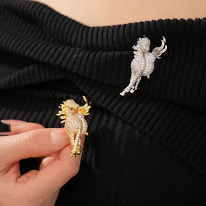 Close-up of gold and silver pegasus brooches with white cubic zirconia on black fabric