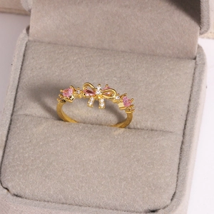 Detail shot of a golden bow ring featuring pink pear-shaped gems and white zircons