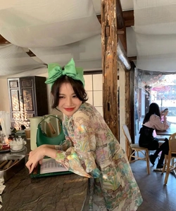 Woman wearing a large green seersucker bow headband with sweet floral print shirt