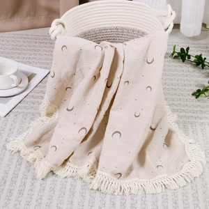 Detail of soft cotton double gauze baby blanket with moon star print and tassel trim