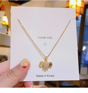 Detail of a golden elephant pendant necklace on a Thank You gift card packaging