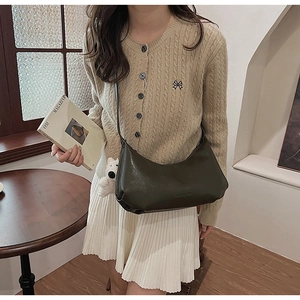Detail of olive green faux leather dumpling bag featuring a white plush puppy charm