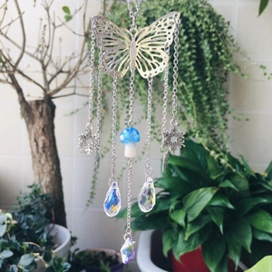 Close-up of crystal suncatcher with silver butterfly, blue mushroom and prism drops
