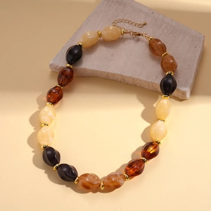 Detail of retro acrylic oval beaded necklace with amber and black stones on stone decor