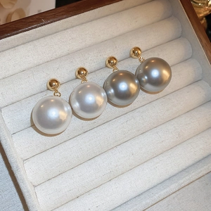 Lustrous white and dark grey pearl stud earrings in gold plating on velvet display