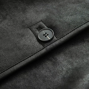 Close-up of matte black leather fabric texture with round buttons and stitching detail