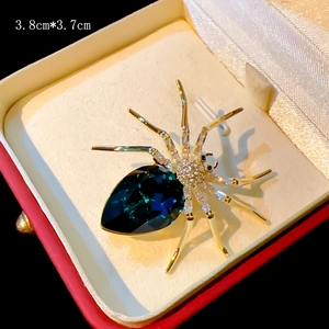 Elegant gold spider brooch with large navy blue pear crystal and small zircons in a gift box