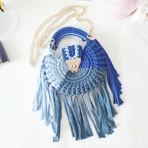Detailed view of handmade crochet crossbody bag featuring blue fringes and metal chain strap