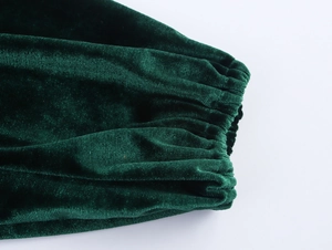 Detail of dark green velvet sleeve with elastic cuff showing soft texture and sheen