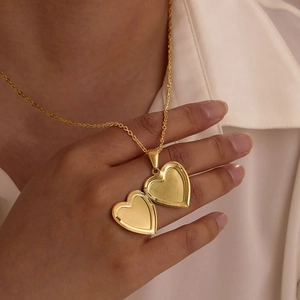 Polished gold heart locket necklace in stainless steel shown open on a model's hand
