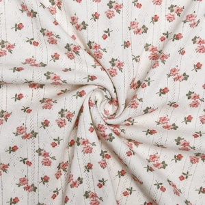Vue détaillée du tricot blanc ajouré avec un délicat imprimé floral rose doux
