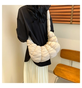 Rear view of model wearing a creamy beige pleated croissant bag with soft quilted fabric
