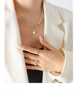 Detail of zircon and freshwater pearl pendant necklace with stylish gold rings on model
