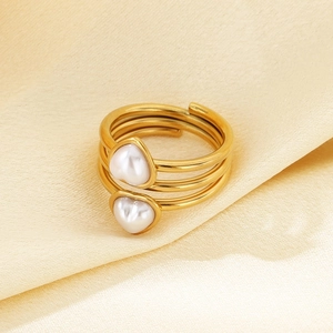 Detail of 18k gold plated spiral ring with two heart-shaped pearls on beige silk fabric