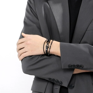 Detail of men's multilayer black leather bracelet with infinity symbol and beaded strands