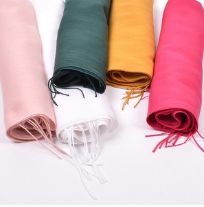 Detail shot of multicolored soft cashmere scarves with fringe in pink white green and yellow