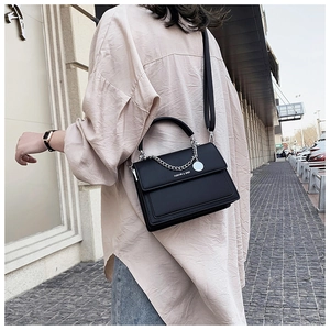 Detail of black leather crossbody bag with silver chain and adjustable shoulder strap
