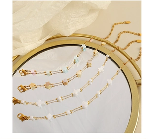 Macro view of gold-plated layering chain bracelets with colorful star and cross beads