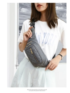 Close-up of gray quilted crossbody bag with multi-zipper pockets and adjustable strap