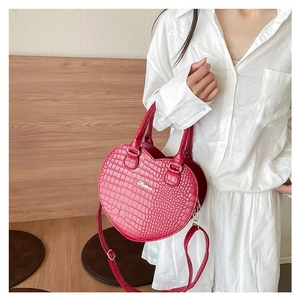Détail du sac à main rouge en forme de cœur effet crocodile avec logo métallique