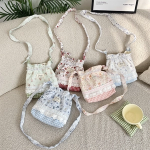 Détail de cinq sacs bandoulière à cordon fleuris avec bordure en dentelle sur un canapé