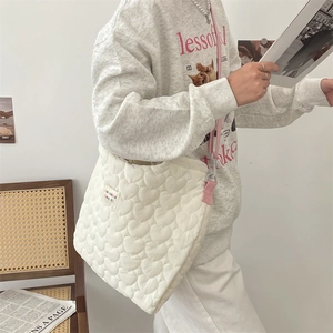 Détail du sac en toile matelassé blanc à cœurs avec bandoulière rose et étiquette