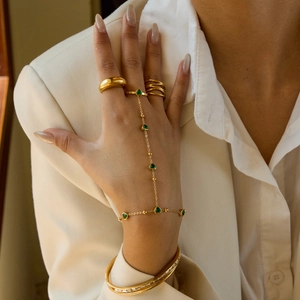 Vue détaillée d'un bracelet main doré avec pierre en cœur vert et bagues assorties