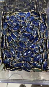Close-up of bulk faceted oval lapis lazuli pendants with gold plated dual-hole connectors