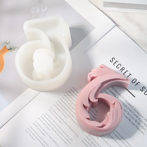 Detailweergave van siliconen mal nummer 6 en roze kaars op een opengeslagen boek