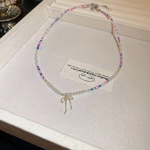 Detail of beaded necklace with faux pearls, colorful seed beads and silver bow charm