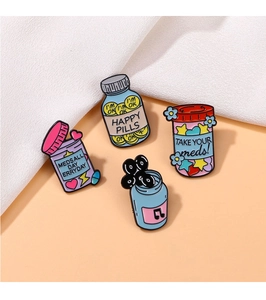 Detail shot of four colorful medical-themed metal enamel pins on soft white fabric