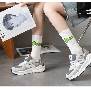 Close-up of white mid-calf athletic socks with green Summer text and casual sneakers