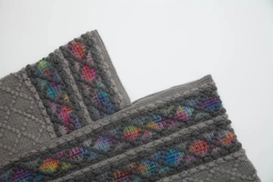 Detailed close-up of ethnic knit poncho showing colorful geometric diamond embroidery patterns