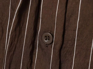 Close-up of brown striped shirt fabric with high-quality resin button detail