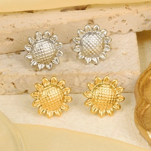 Macro shot of 18k gold and silver sunflower earrings on a textured stone surface