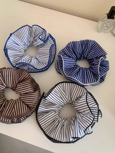 Detailed view of oversized striped fabric scrunchies in blue, brown, and black colors