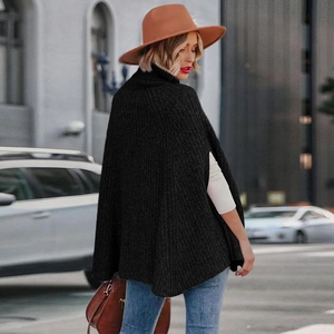 Vista posteriore in stile street di un poncho nero a maglia grossa con collo alto