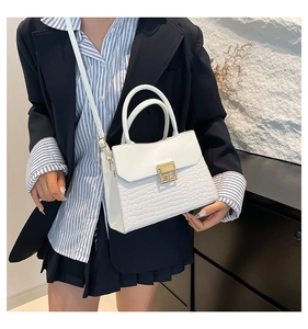 Detailed view of white crocodile pattern handbag with gold hardware and shoulder strap
