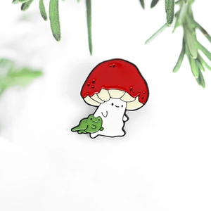 Detail of red mushroom man and green frog enamel pin with polished alloy finish