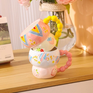 Hand-painted ceramic breakfast mugs with strawberry and peach patterns on a wooden table