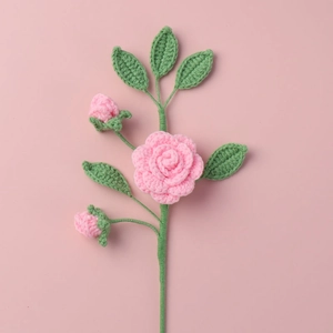 Ramo di camelia rosa fatto a mano all'uncinetto con foglie su sfondo rosa puro