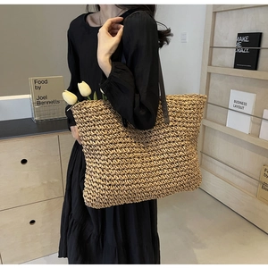 Close-up of large straw tote bag featuring woven texture and dark leather shoulder straps
