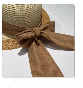 Close-up of wide brown linen bow and fine straw texture on a summer sun hat