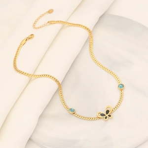 Gold butterfly snake chain necklace with turquoise accents on marble background