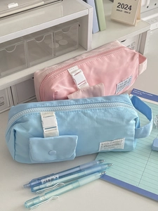 Detail showing high-capacity pencil bags in pastel colors with buckle and side strap