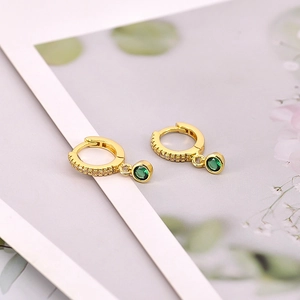 Detail showing gold hoop earrings with green zircon pendants and micro-pave setting