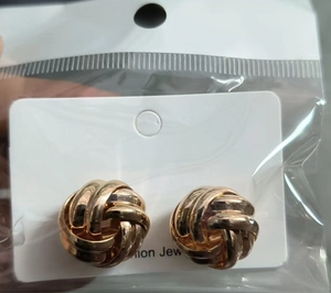 Close-up of golden twisted geometric stud earrings on a fashion jewelry display card