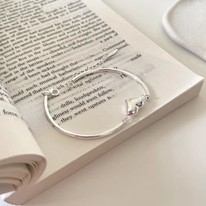 Elegant S925 sterling silver heart bracelet displayed on an open book in natural light